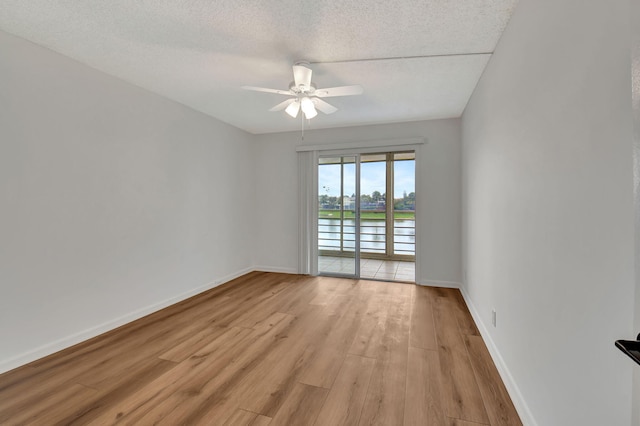 unfurnished room featuring a textured ceiling, light wood-type flooring, and ceiling fan