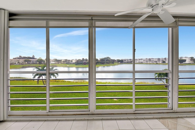 unfurnished sunroom featuring plenty of natural light, ceiling fan, and a water view