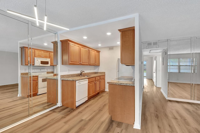 kitchen featuring light stone countertops, sink, a textured ceiling, white appliances, and light wood-type flooring