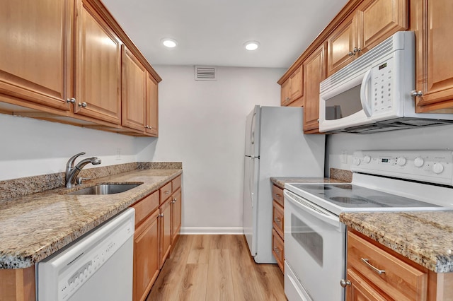 kitchen with light stone countertops, sink, white appliances, and light wood-type flooring