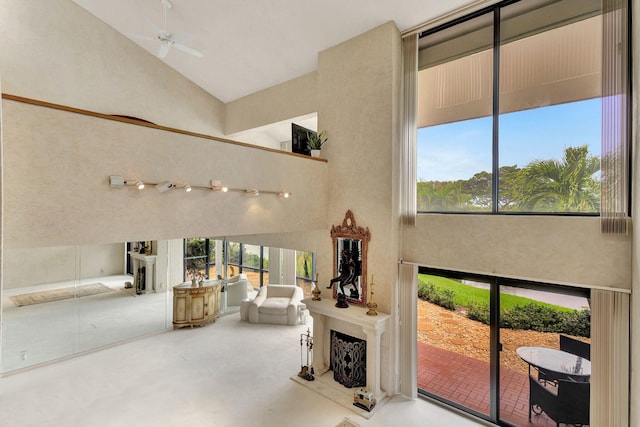 interior space with ceiling fan, high vaulted ceiling, and concrete flooring