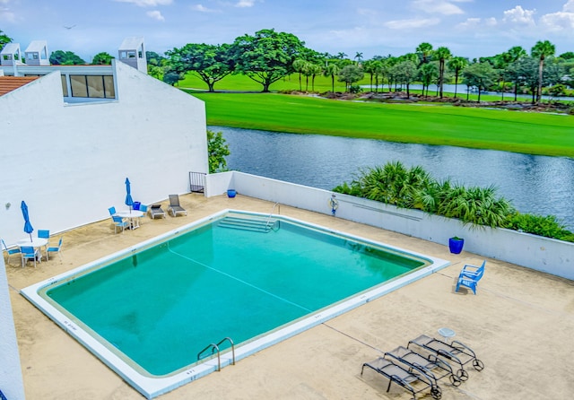 view of swimming pool with a patio area, a water view, and a yard