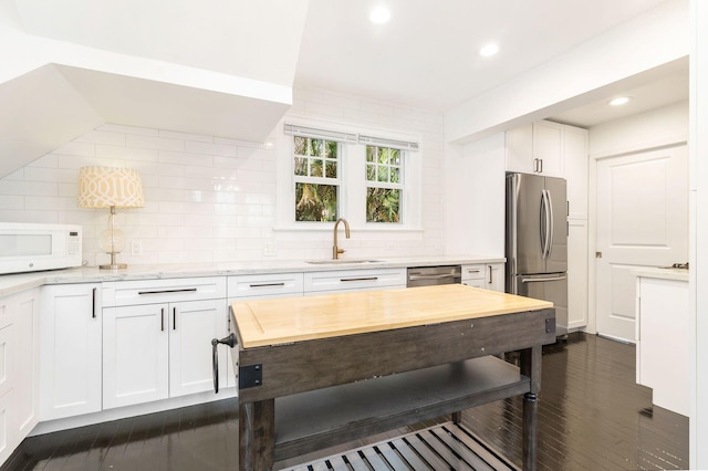 kitchen with tasteful backsplash, white cabinetry, sink, and appliances with stainless steel finishes