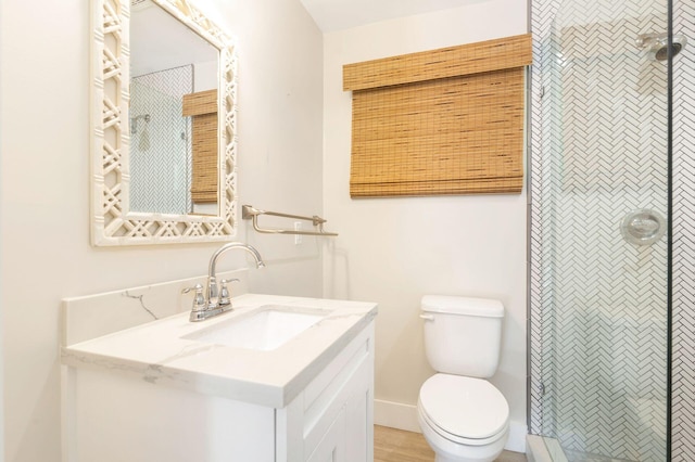 bathroom with a tile shower, vanity, and toilet