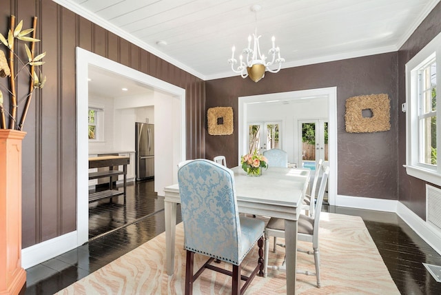 dining space featuring dark hardwood / wood-style flooring, crown molding, french doors, and an inviting chandelier