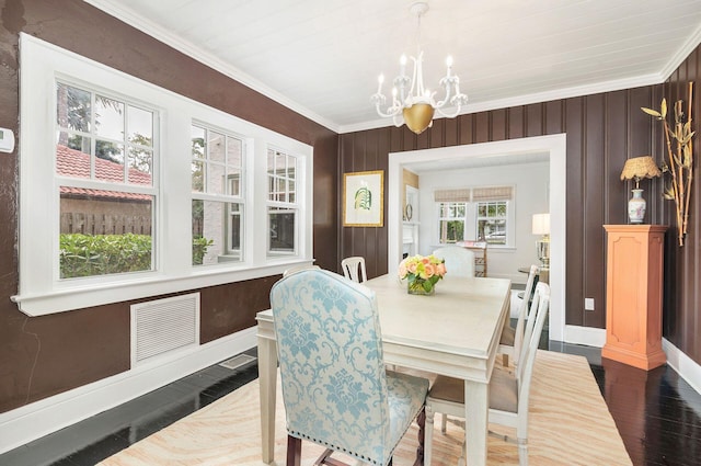 dining space featuring crown molding, dark wood-type flooring, and an inviting chandelier