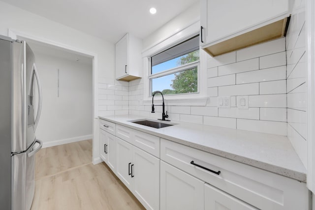 kitchen with stainless steel fridge, sink, white cabinets, and light hardwood / wood-style floors