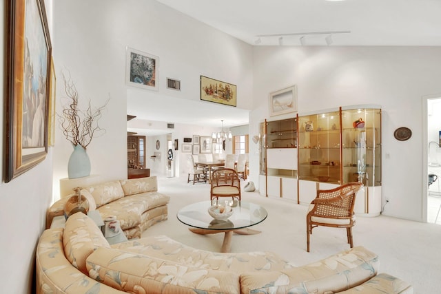 living room with a high ceiling, carpet floors, track lighting, and an inviting chandelier