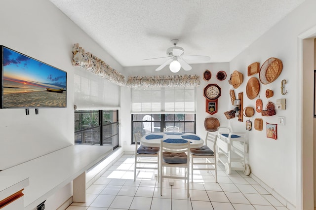 tiled dining space featuring ceiling fan, a healthy amount of sunlight, and a textured ceiling