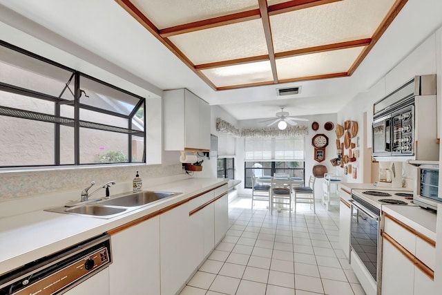 kitchen featuring electric stove, sink, light tile patterned floors, dishwashing machine, and white cabinetry