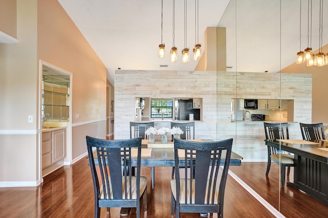 dining space with dark hardwood / wood-style flooring, a towering ceiling, and sink