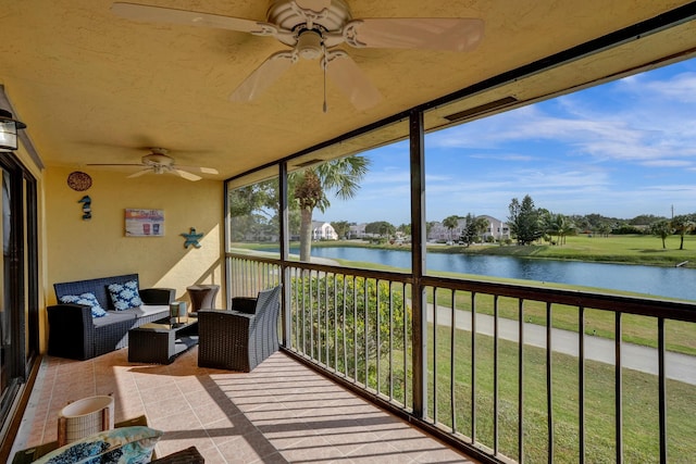 sunroom with ceiling fan and a water view