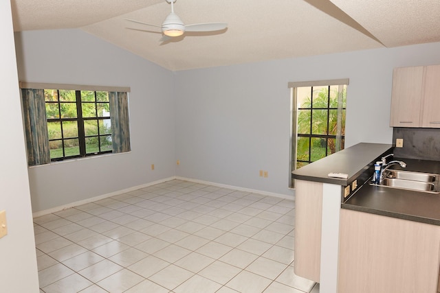 kitchen featuring kitchen peninsula, light brown cabinetry, vaulted ceiling, ceiling fan, and sink