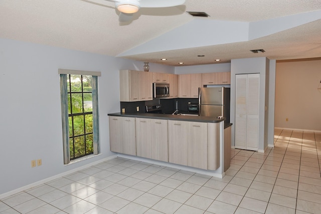 kitchen featuring ceiling fan, kitchen peninsula, lofted ceiling, light brown cabinetry, and appliances with stainless steel finishes