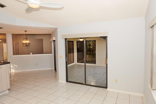 tiled spare room featuring ceiling fan with notable chandelier and vaulted ceiling