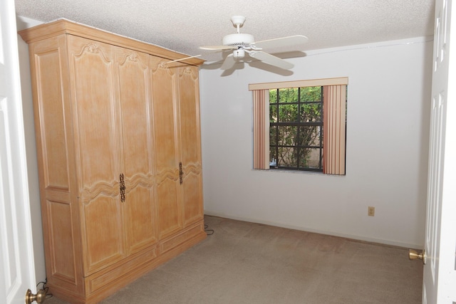 unfurnished bedroom featuring ceiling fan, light colored carpet, and a textured ceiling