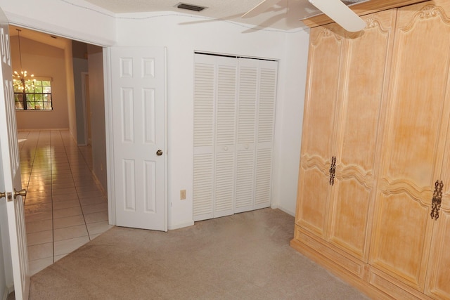 unfurnished bedroom with ceiling fan with notable chandelier, light carpet, and a closet