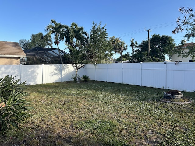 view of yard with a lanai and an outdoor fire pit