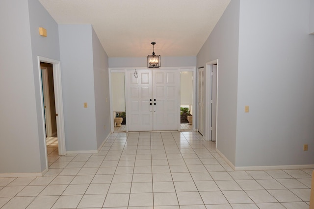 tiled entryway with lofted ceiling and a notable chandelier