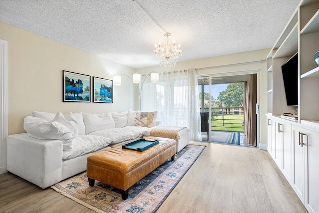 living room with light wood-type flooring, a textured ceiling, and an inviting chandelier