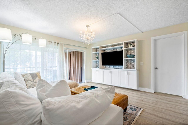 living room featuring an inviting chandelier, a textured ceiling, and light hardwood / wood-style flooring