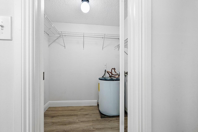 spacious closet with wood-type flooring and water heater