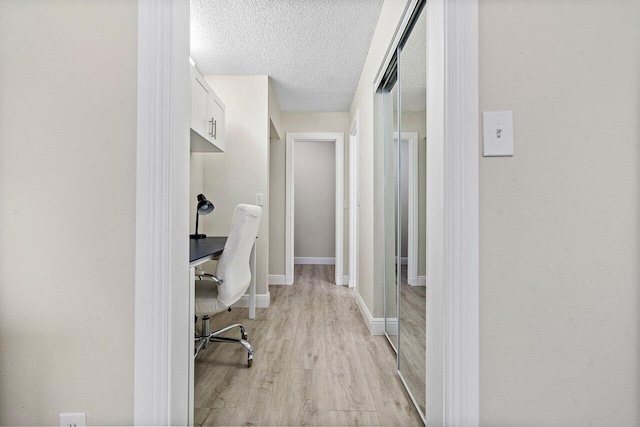 hallway featuring light wood-type flooring and a textured ceiling