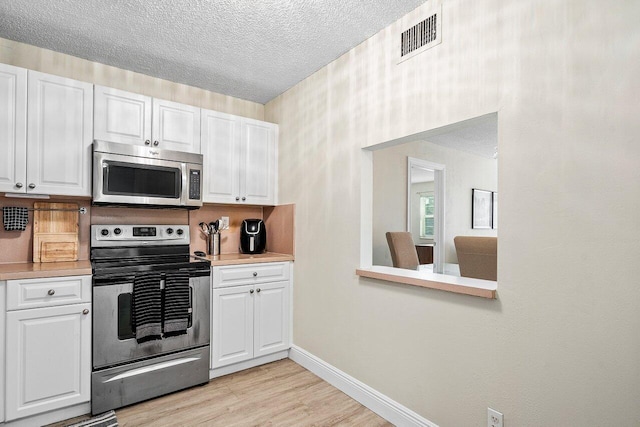 kitchen with white cabinetry, light wood-type flooring, and appliances with stainless steel finishes