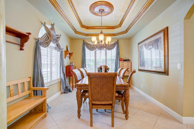 tiled dining room with a chandelier, ornamental molding, and a tray ceiling