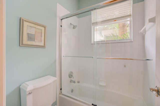 bathroom featuring toilet and combined bath / shower with glass door