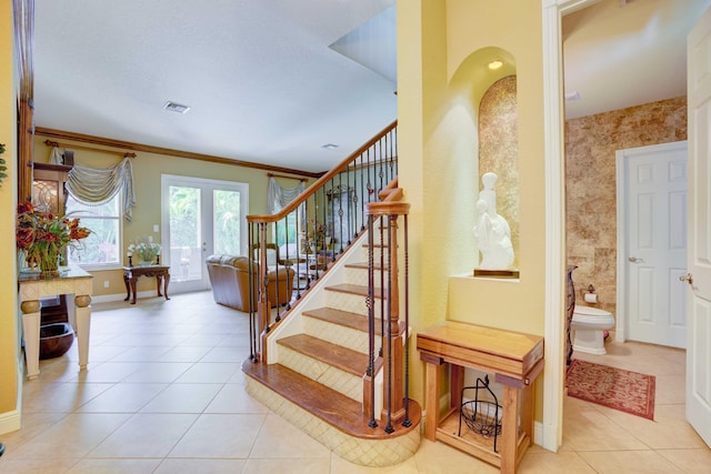 stairway with tile patterned flooring, french doors, and ornamental molding