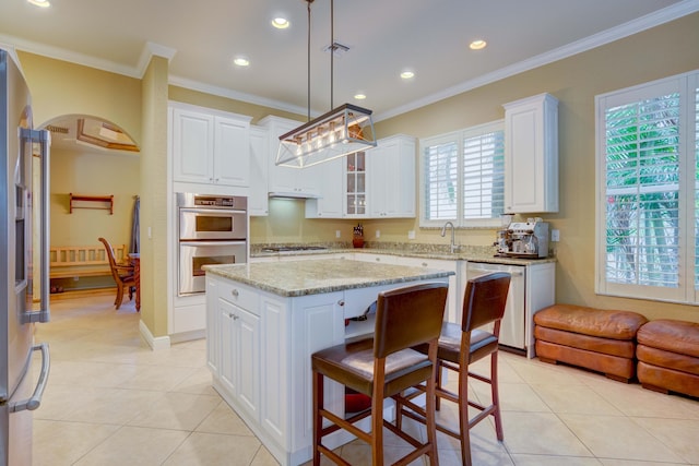 kitchen featuring stainless steel appliances, crown molding, white cabinets, a kitchen island, and hanging light fixtures