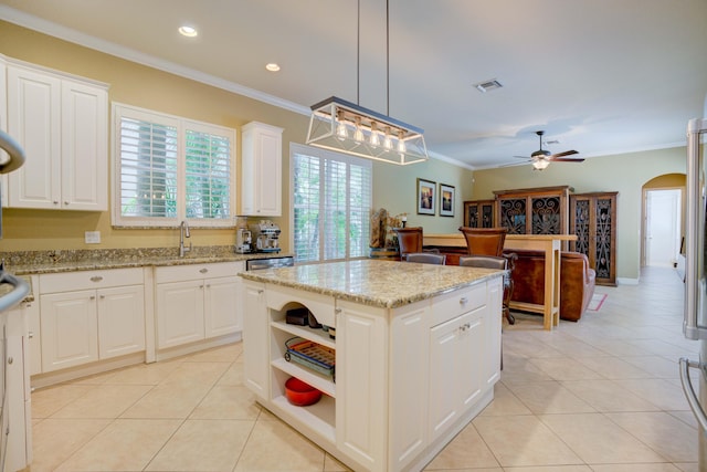 kitchen featuring light stone countertops, ceiling fan, a center island, white cabinetry, and hanging light fixtures