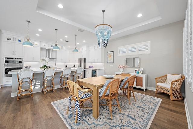 dining area featuring a raised ceiling, dark hardwood / wood-style flooring, beverage cooler, and a notable chandelier