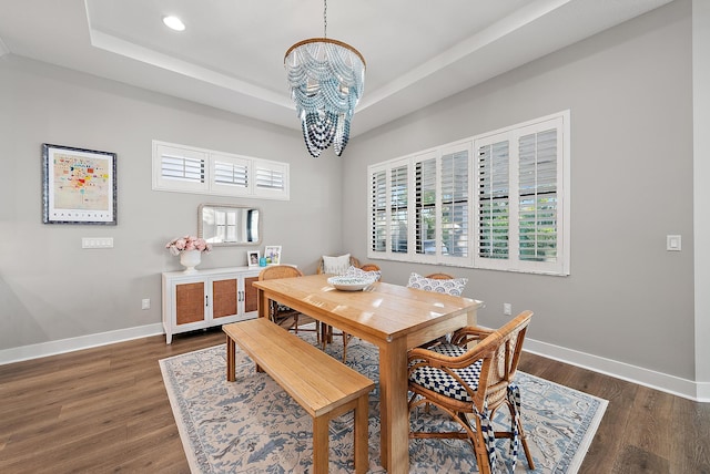 dining room featuring a chandelier, a tray ceiling, and dark wood-type flooring