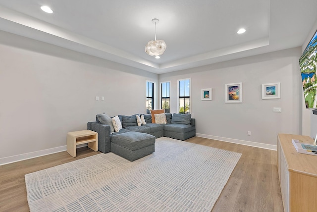 living room featuring a tray ceiling and light hardwood / wood-style floors