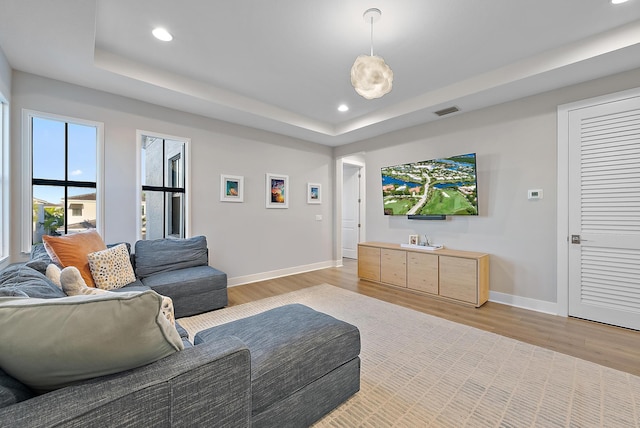 living room featuring a tray ceiling and light hardwood / wood-style floors