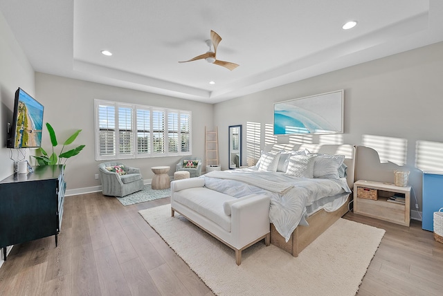 bedroom with a raised ceiling, ceiling fan, and light hardwood / wood-style floors