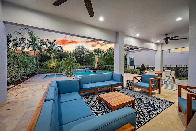 patio terrace at dusk with a fenced in pool, outdoor lounge area, and ceiling fan