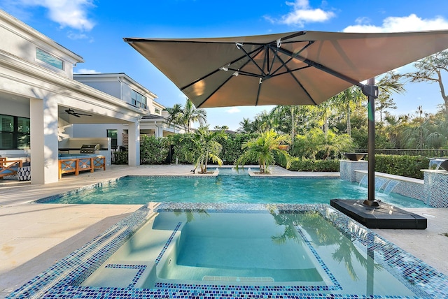 view of swimming pool with an in ground hot tub, an outdoor kitchen, pool water feature, ceiling fan, and a patio