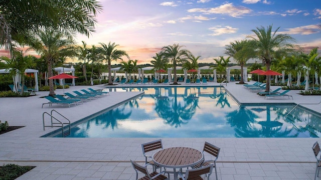 pool at dusk with a patio area