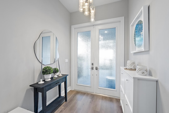 doorway featuring french doors, light wood-type flooring, and an inviting chandelier