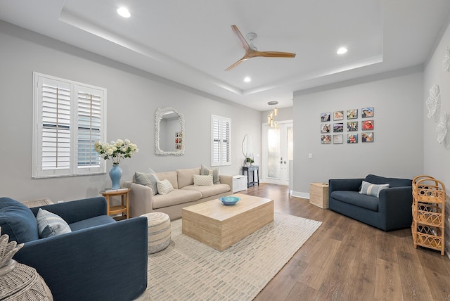 living room with hardwood / wood-style floors, a tray ceiling, and ceiling fan