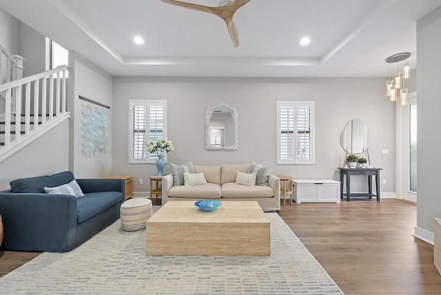 living room with a tray ceiling, hardwood / wood-style floors, and an inviting chandelier