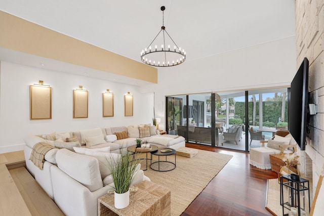 living room with a high ceiling, hardwood / wood-style flooring, and a notable chandelier