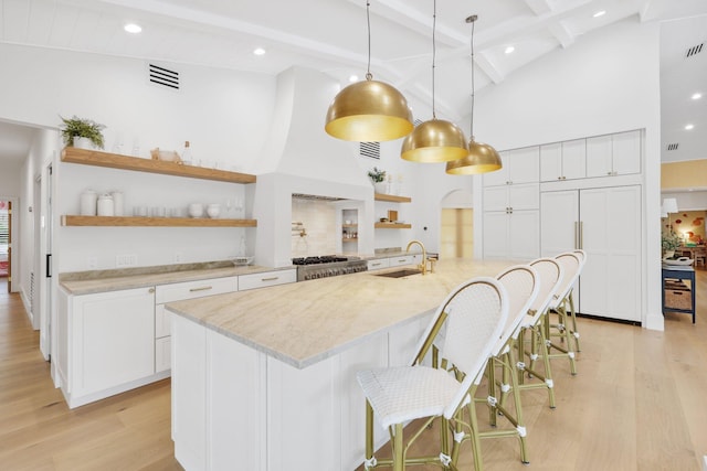 kitchen featuring a breakfast bar, white cabinets, sink, beamed ceiling, and decorative light fixtures