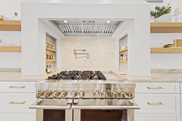 kitchen featuring double oven range, backsplash, white cabinetry, and light stone counters