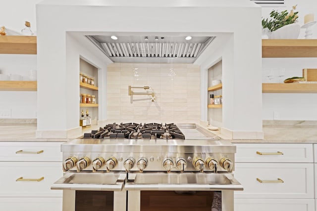 kitchen with tasteful backsplash, double oven range, built in features, light stone countertops, and white cabinets