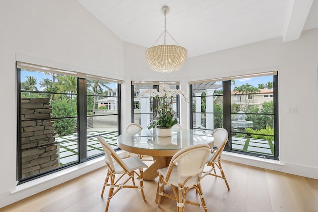 dining room featuring an inviting chandelier, lofted ceiling with beams, and light wood-type flooring