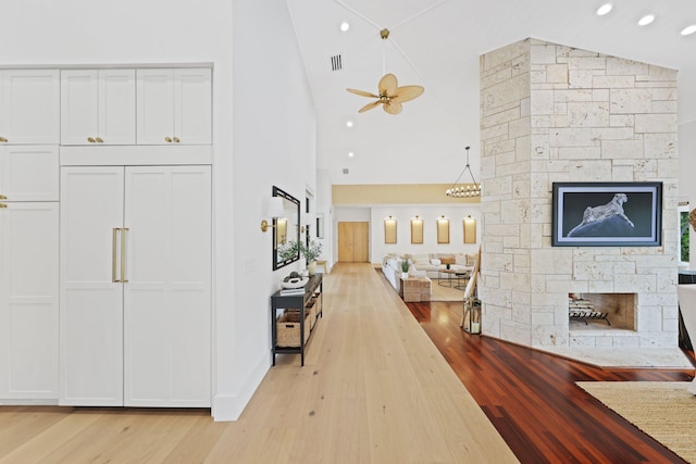 hall with high vaulted ceiling and light wood-type flooring